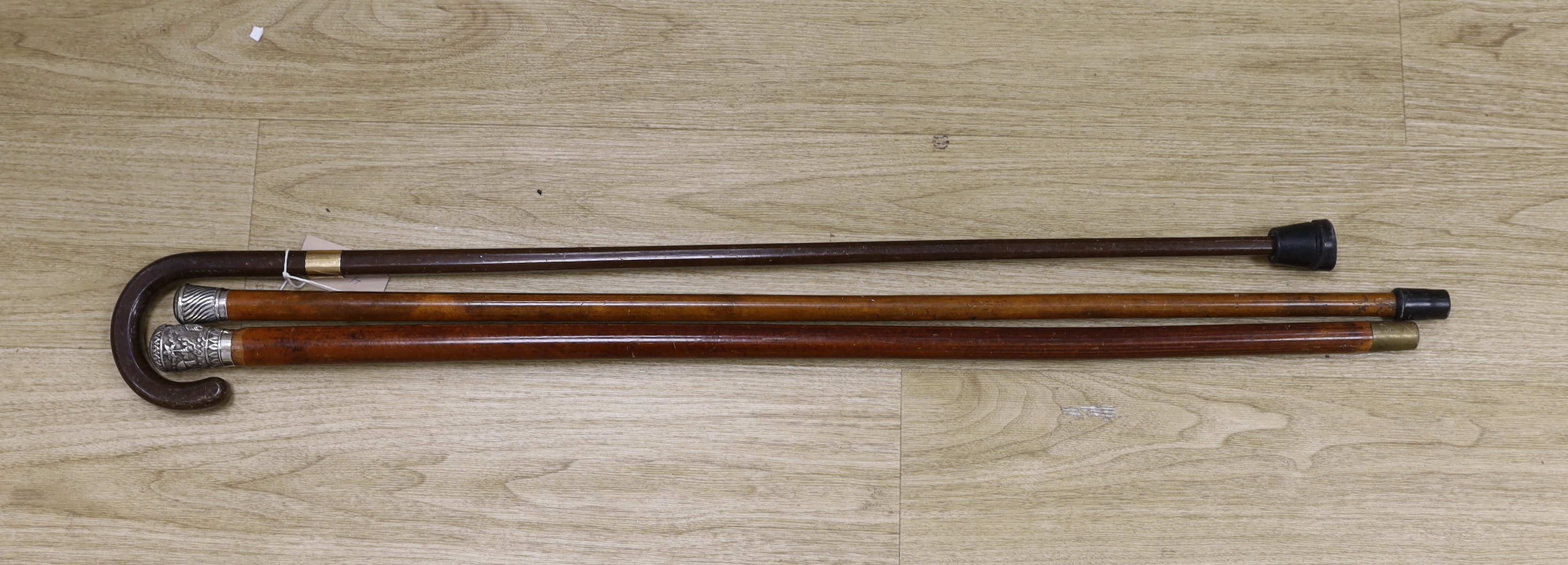 A 9ct gold mounted walking stick from Harrods and two white metal mounted malacca canes